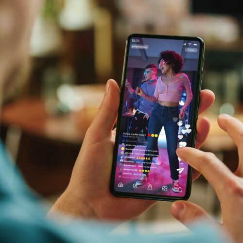 Close-up of hands holding a smartphone displaying a social media video feed, representing digital content consumption